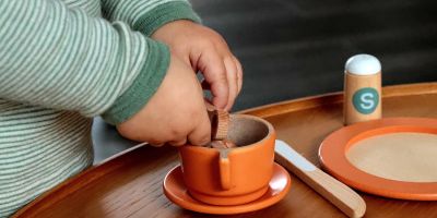 Kinderhände spielen mit Spielzeuggeschirr